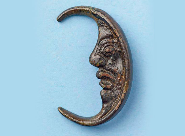A piece of bronze jewellery shaped like the Man in the Moon
