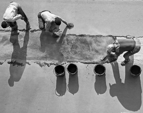 Men building an asphalt road by hand.