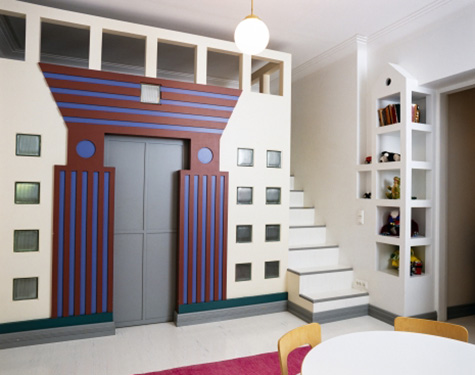 Huone, jossa seinämaalauksia, kaappikello ja huonekaluja.